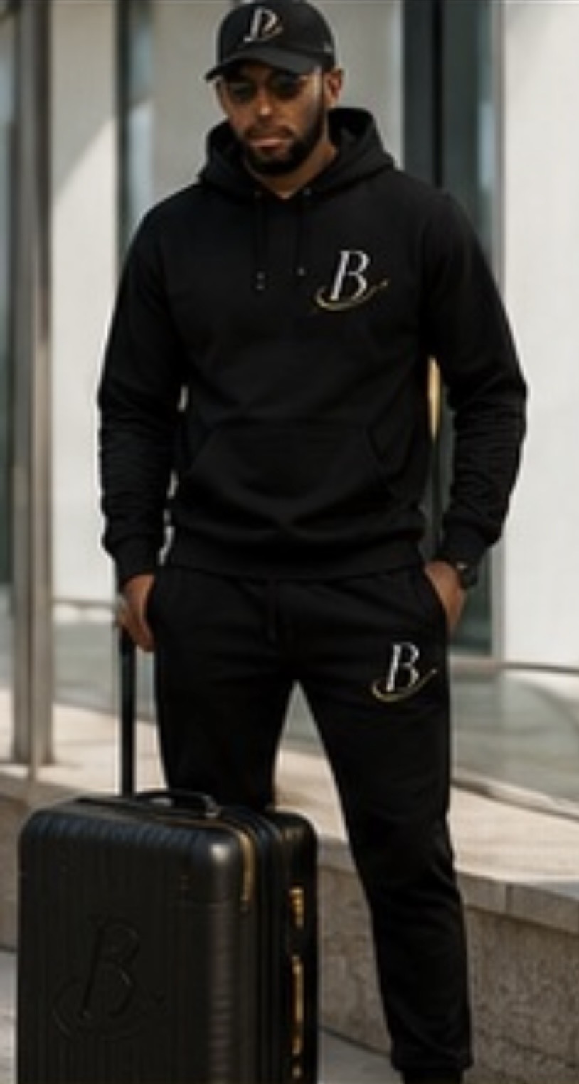 A traveler in a black Baecationing hoodie with a matching black carry-on suitcase